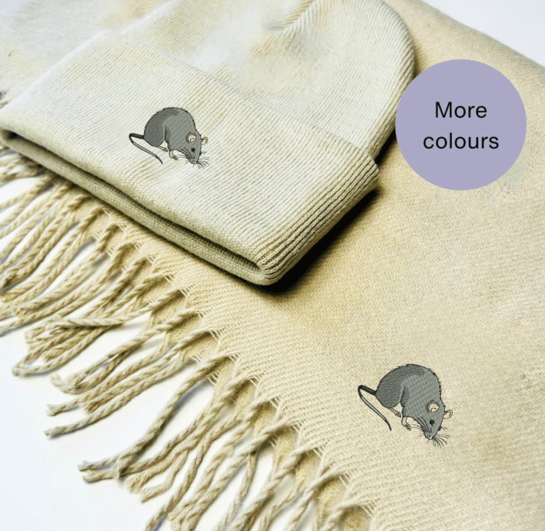 A cozy winter scarf and beanie hat set featuring an intricately embroidered rat design. Available in red, natural, navy blue, black, and grey, this unisex set is perfect for rat lovers and offers warmth and style for chilly days.
